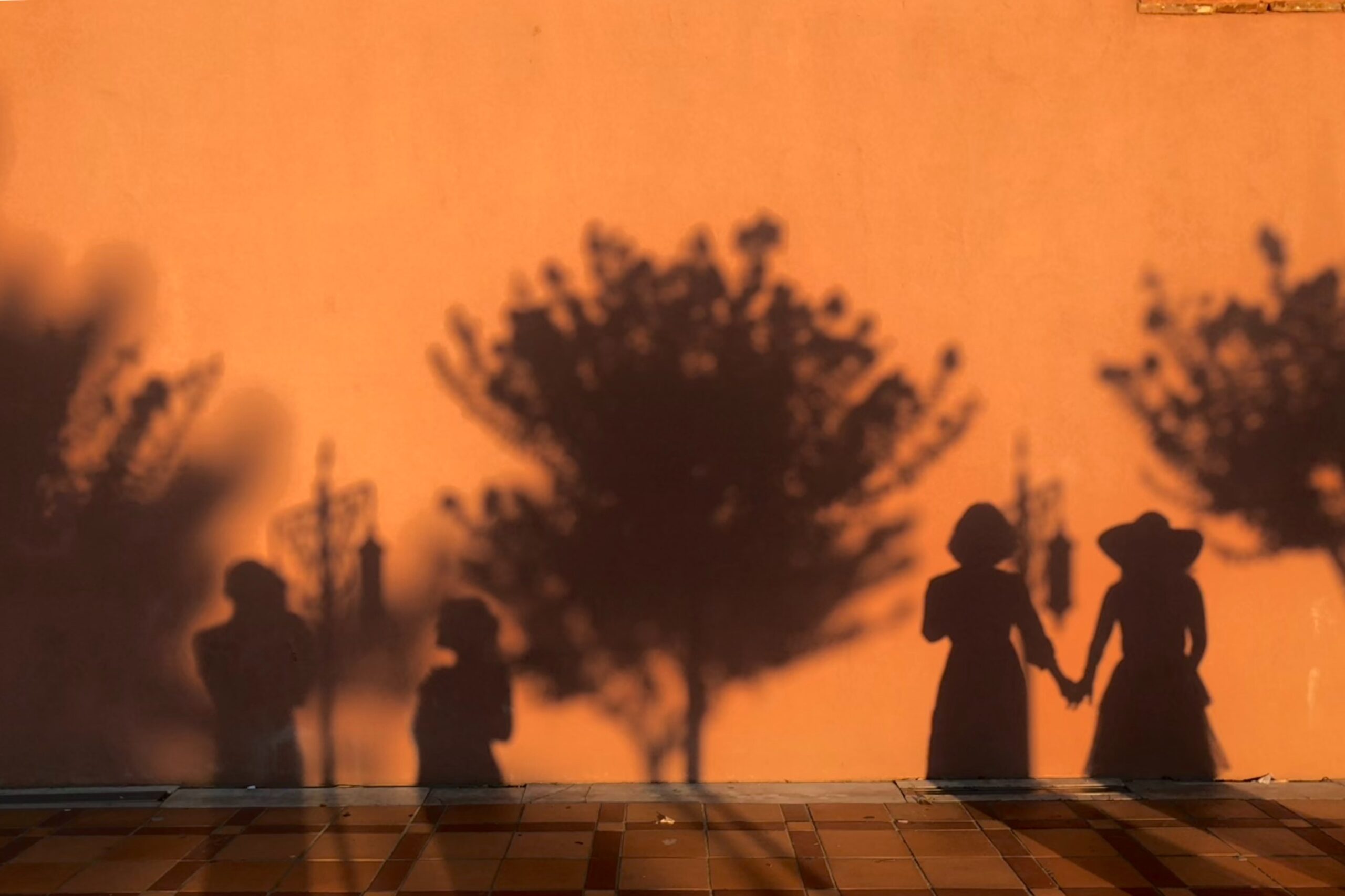 Photo of people silhouetted against an orange wall