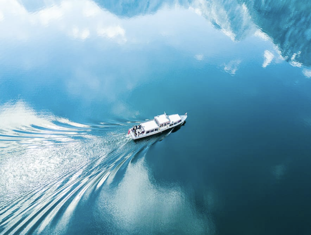 A ship moves through a body of water, leaving waves in its wake